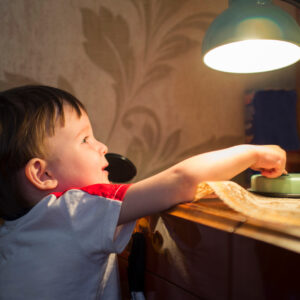 Child reaching for a lamp in a cozy room.