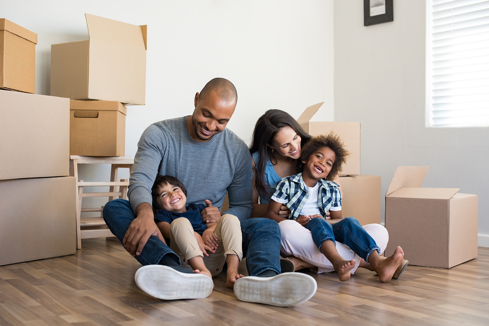 Happy family sitting on the floor among moving boxes.