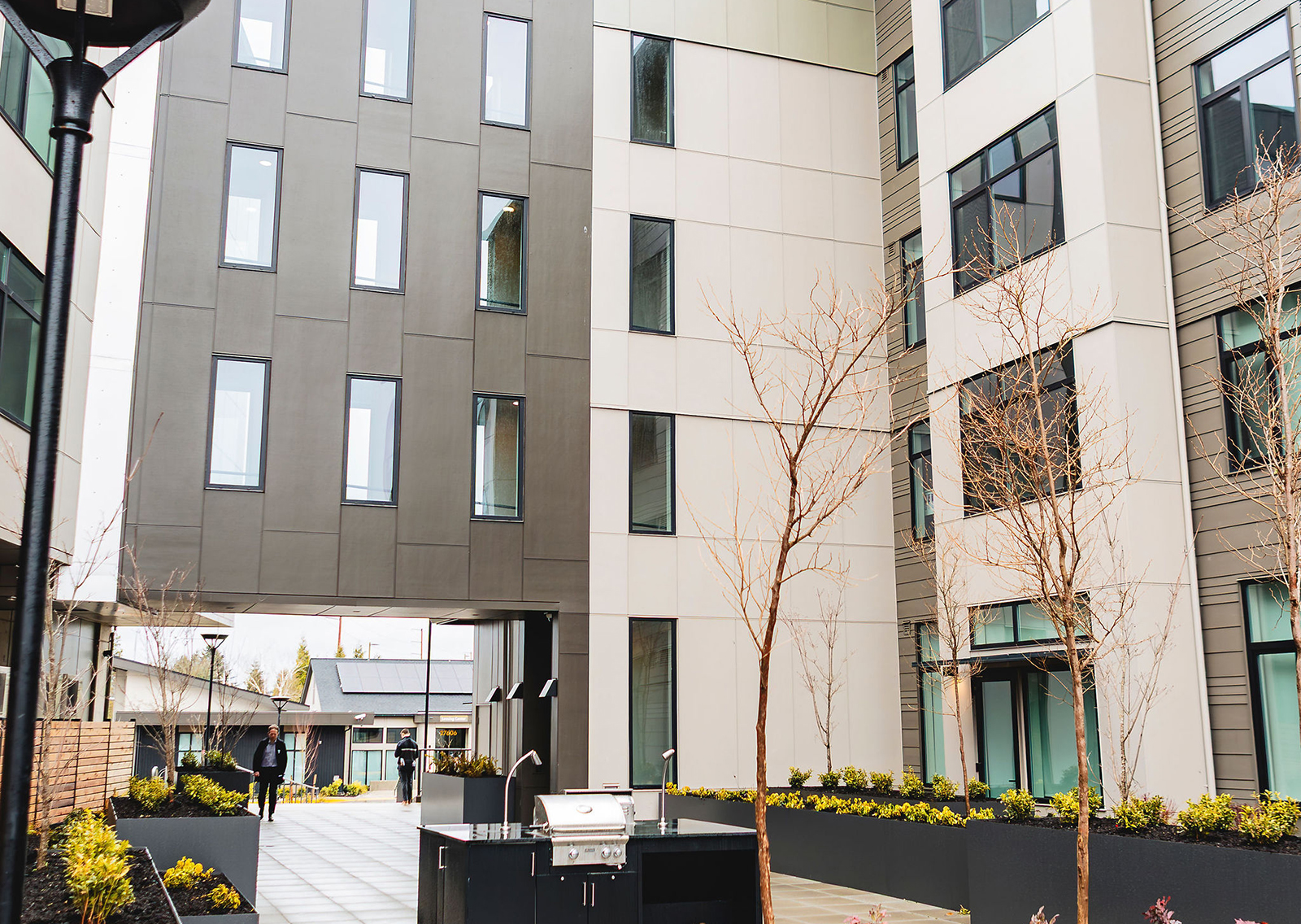 Modern courtyard with buildings, landscaping, and grilling area.