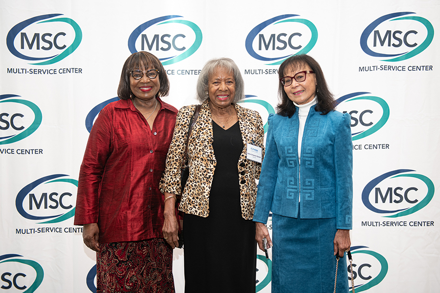 Three women posing at a multi-service center event.