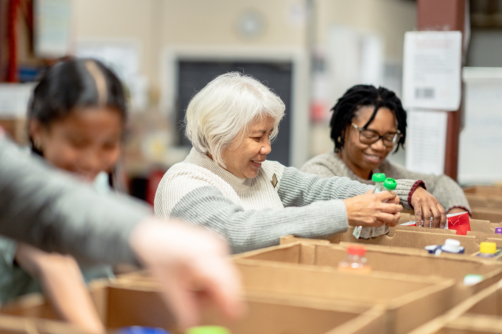 Group of people organizing items in cardboard boxes smiling.