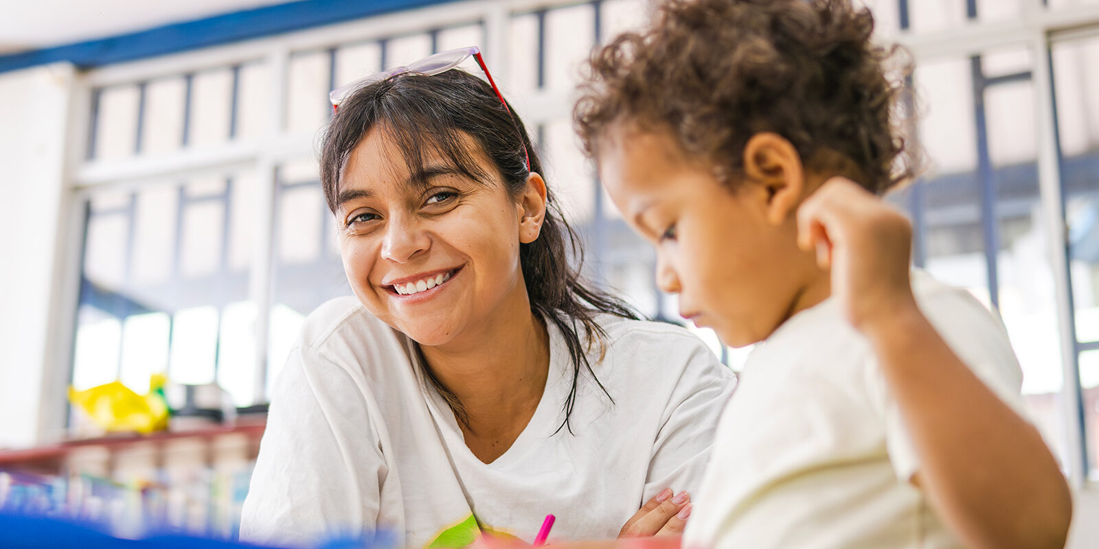 Smiling woman interacts with a focused child. Happy moment.