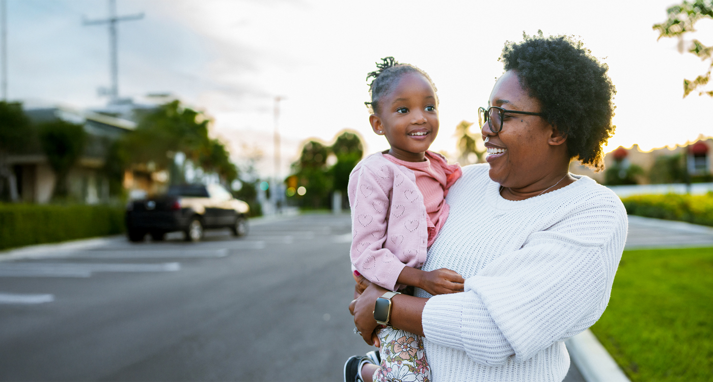 Woman holding young child smiling outside