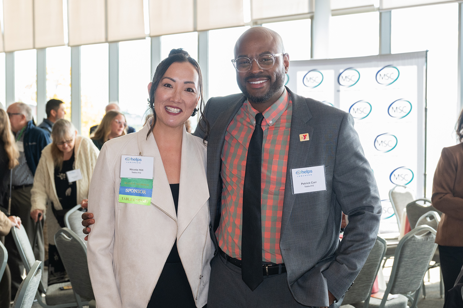 Two smiling individuals pose at a professional event.