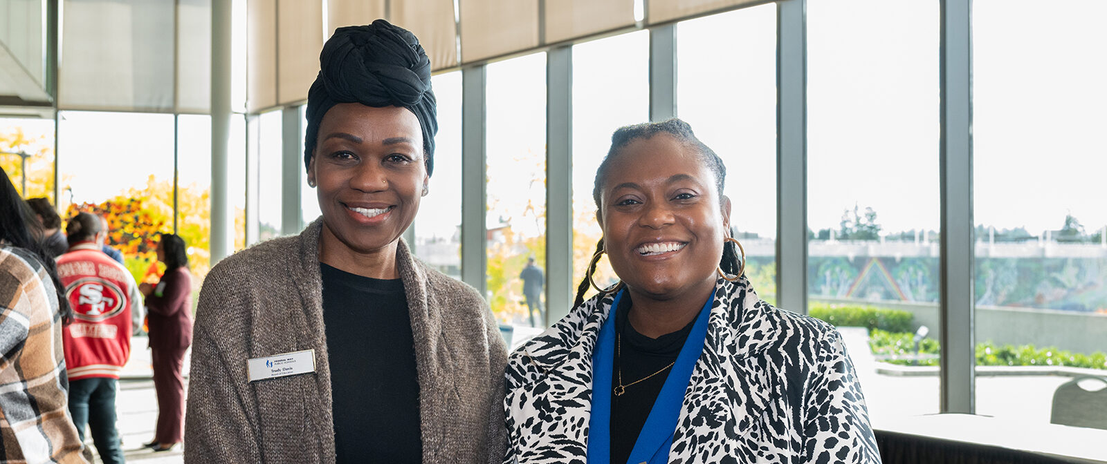Two smiling women posing indoors with natural light.