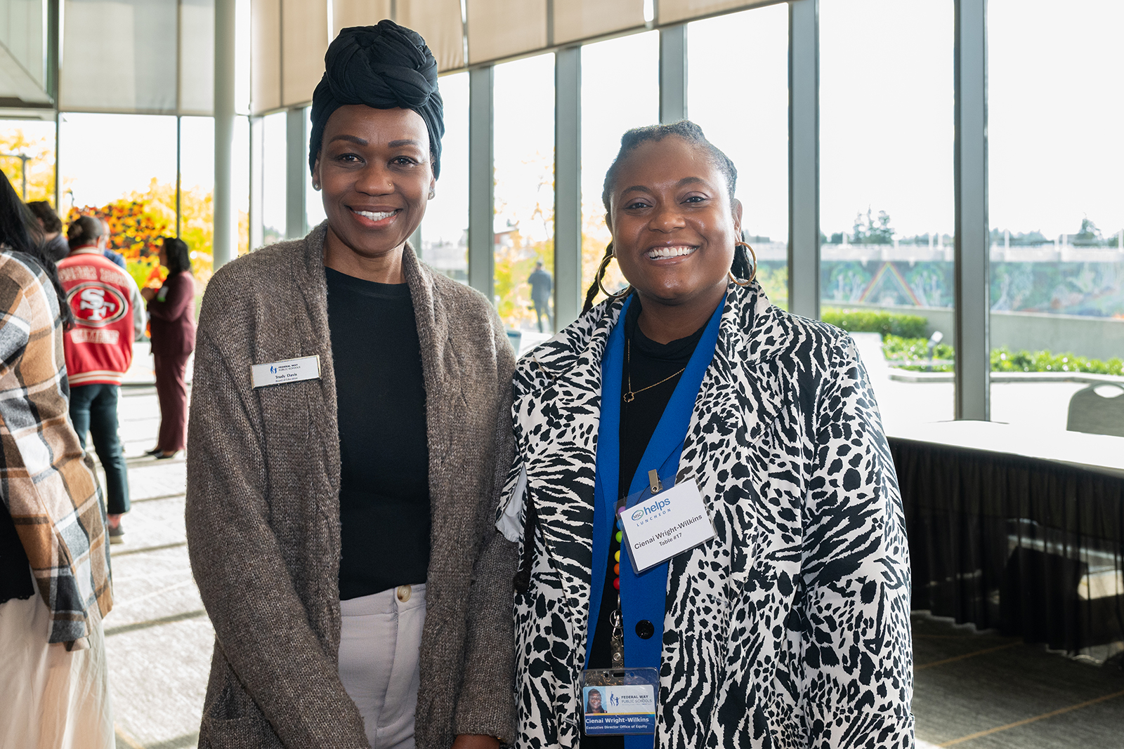 Two smiling women posing indoors with natural light.