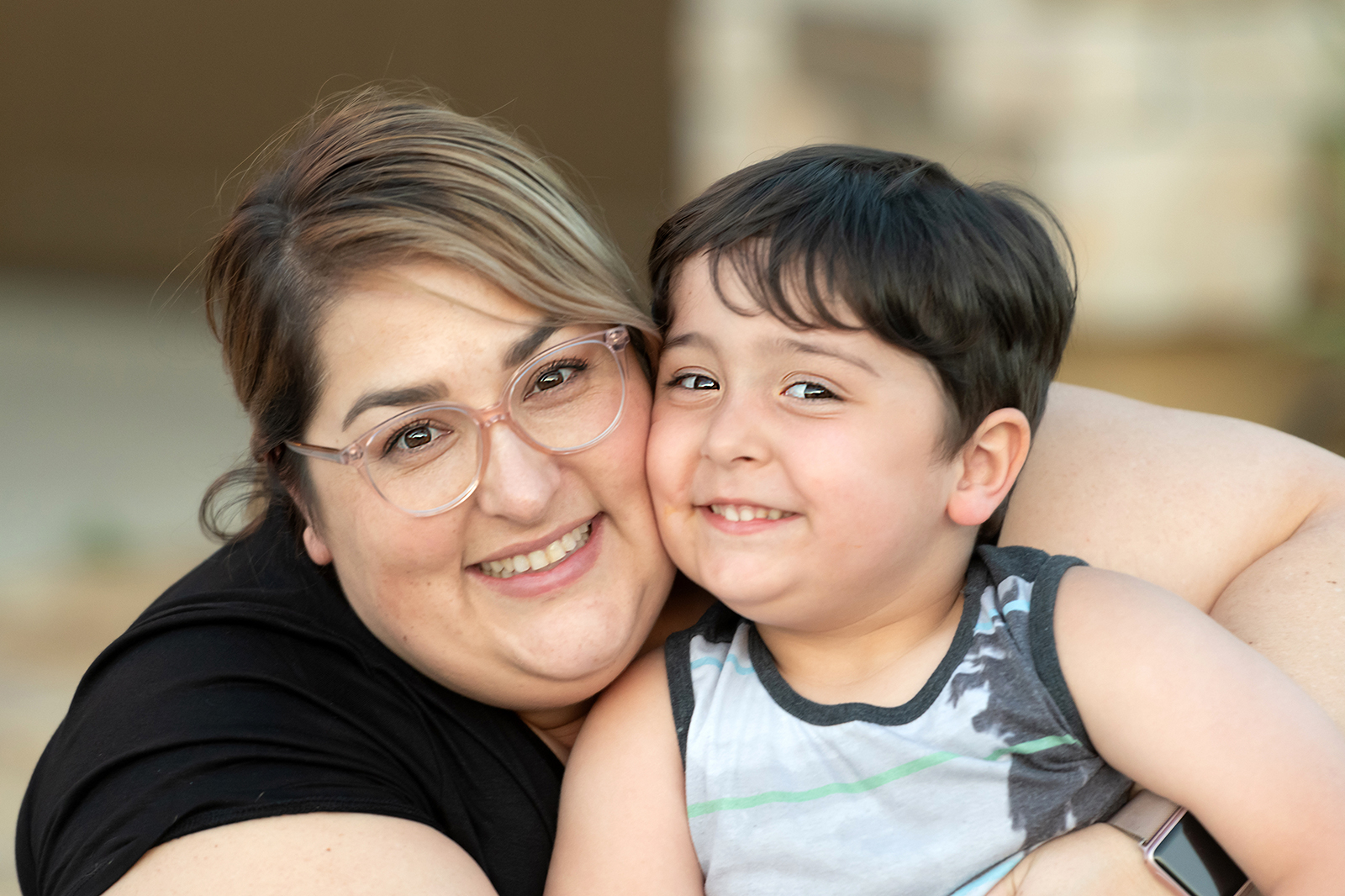 A smiling woman and child embrace joyfully.