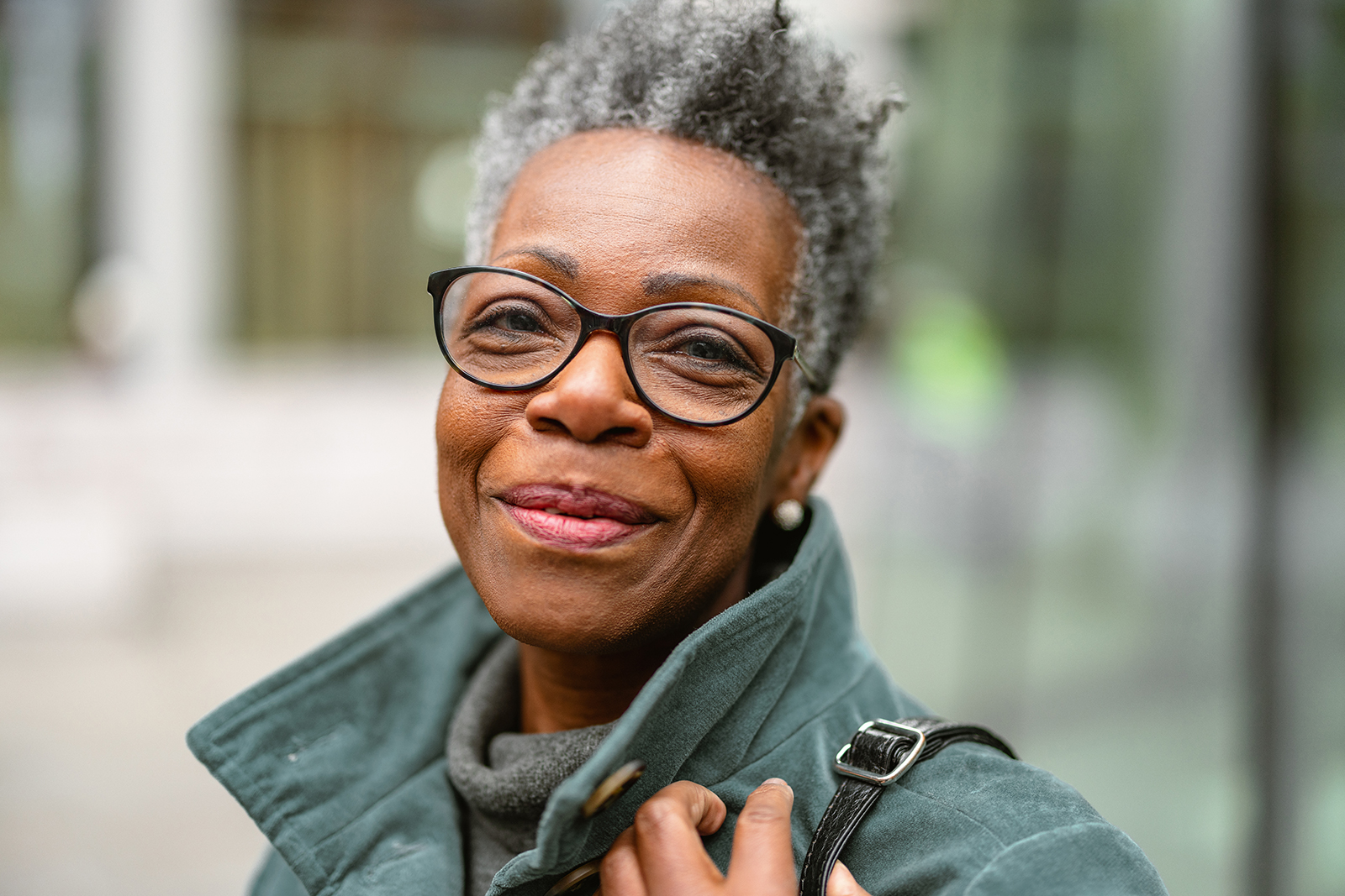 Smiling woman with short grey hair and glasses.