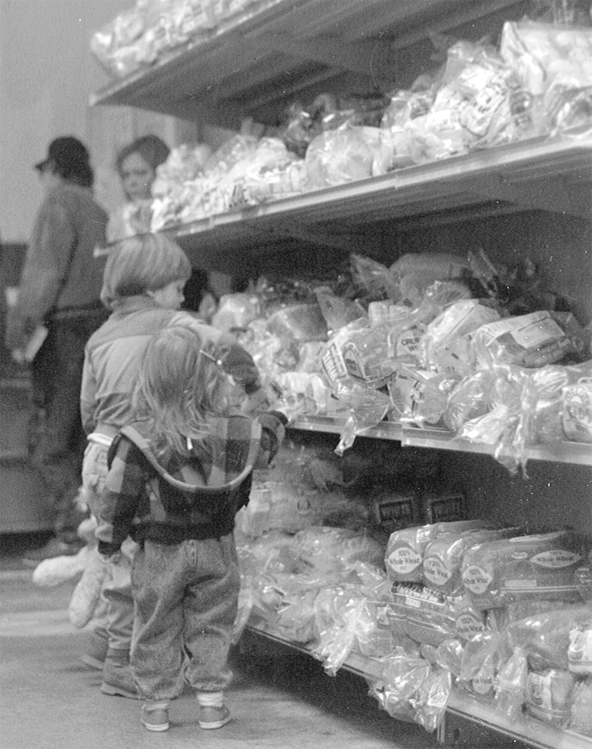 Children observing bread on grocery store shelves.