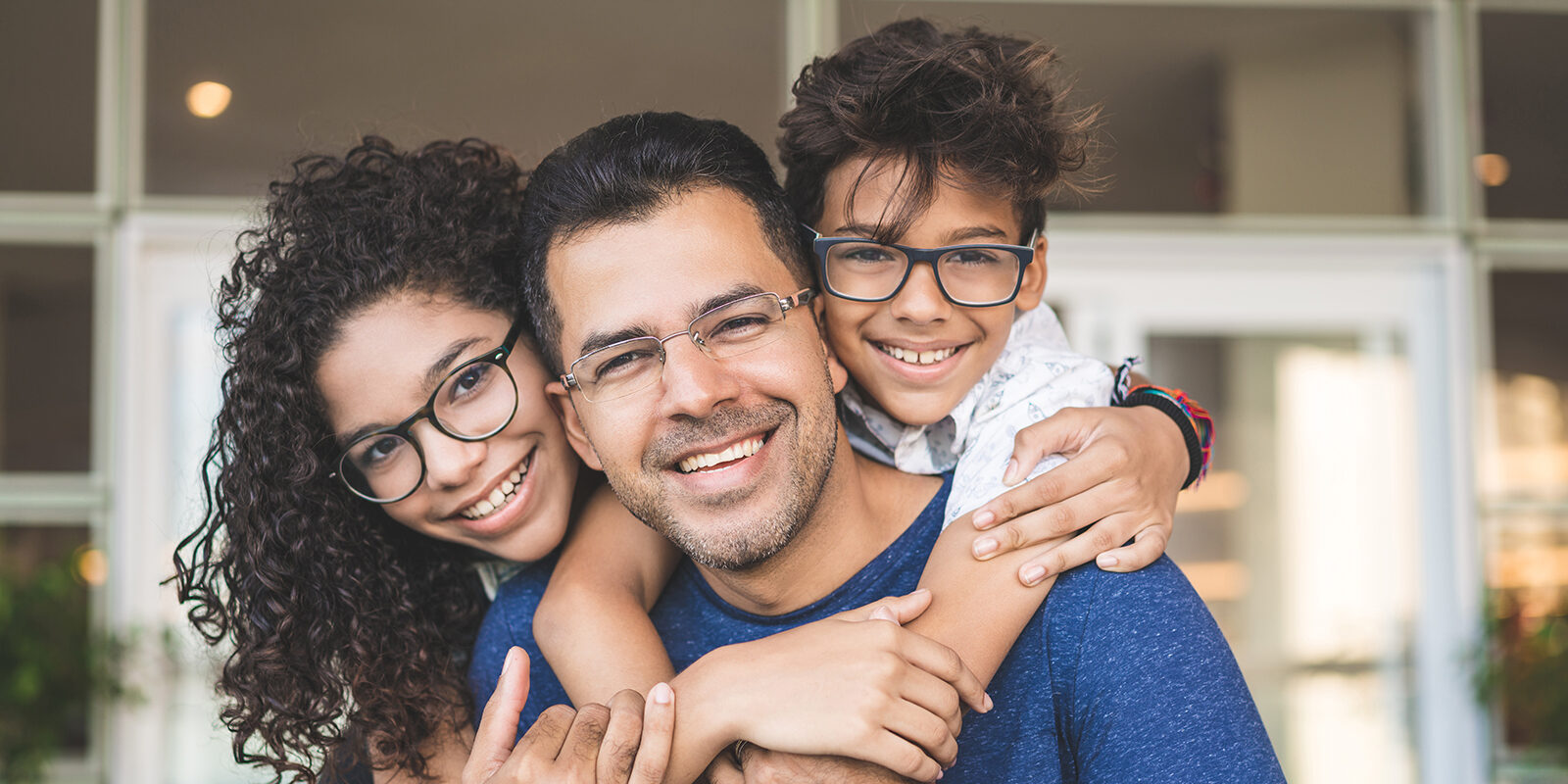 A happy father and his two children smiling together.