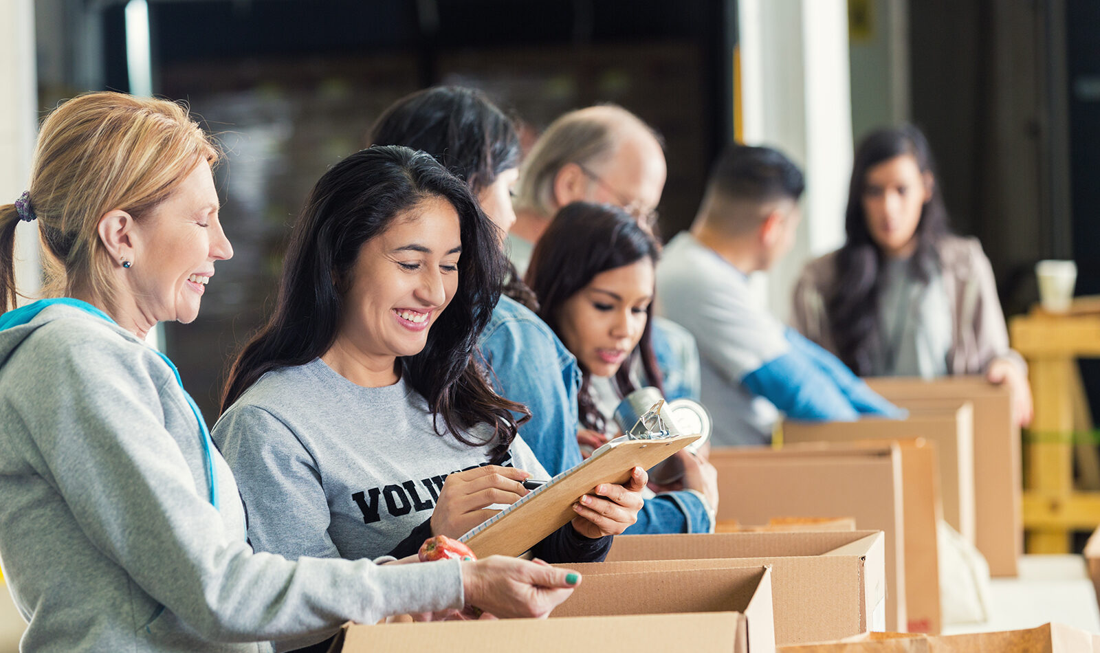 Volunteers packing boxes with smiles and teamwork.