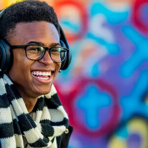 Young man smiling with headphones on in front of colorful wall